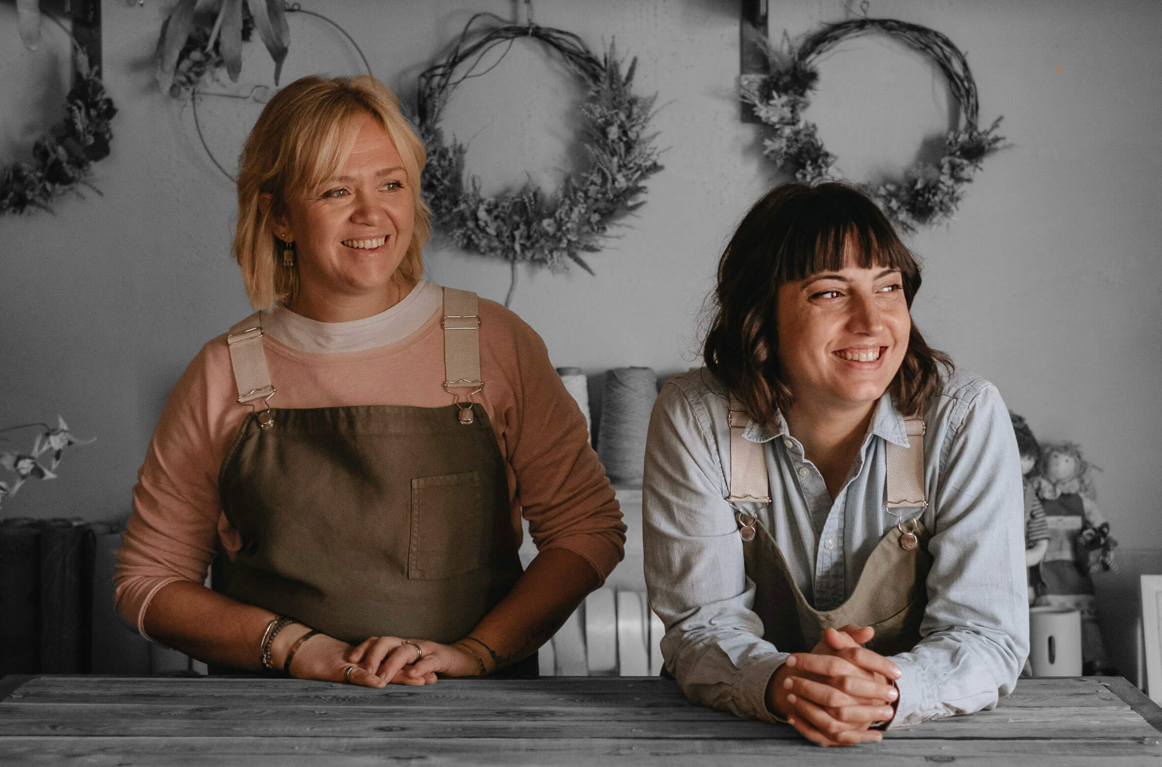 Claudia e Rachele dietro il bancone, alle loro spalle ghirlande di fiori essiccati